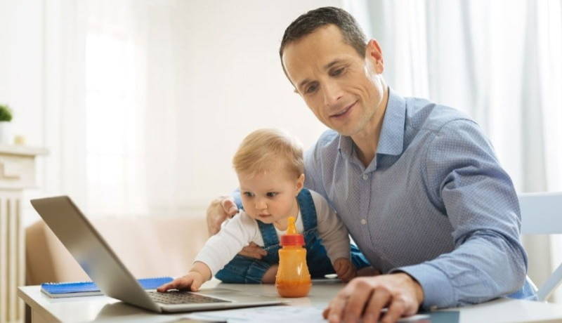 A man working at home and taking care with his child.